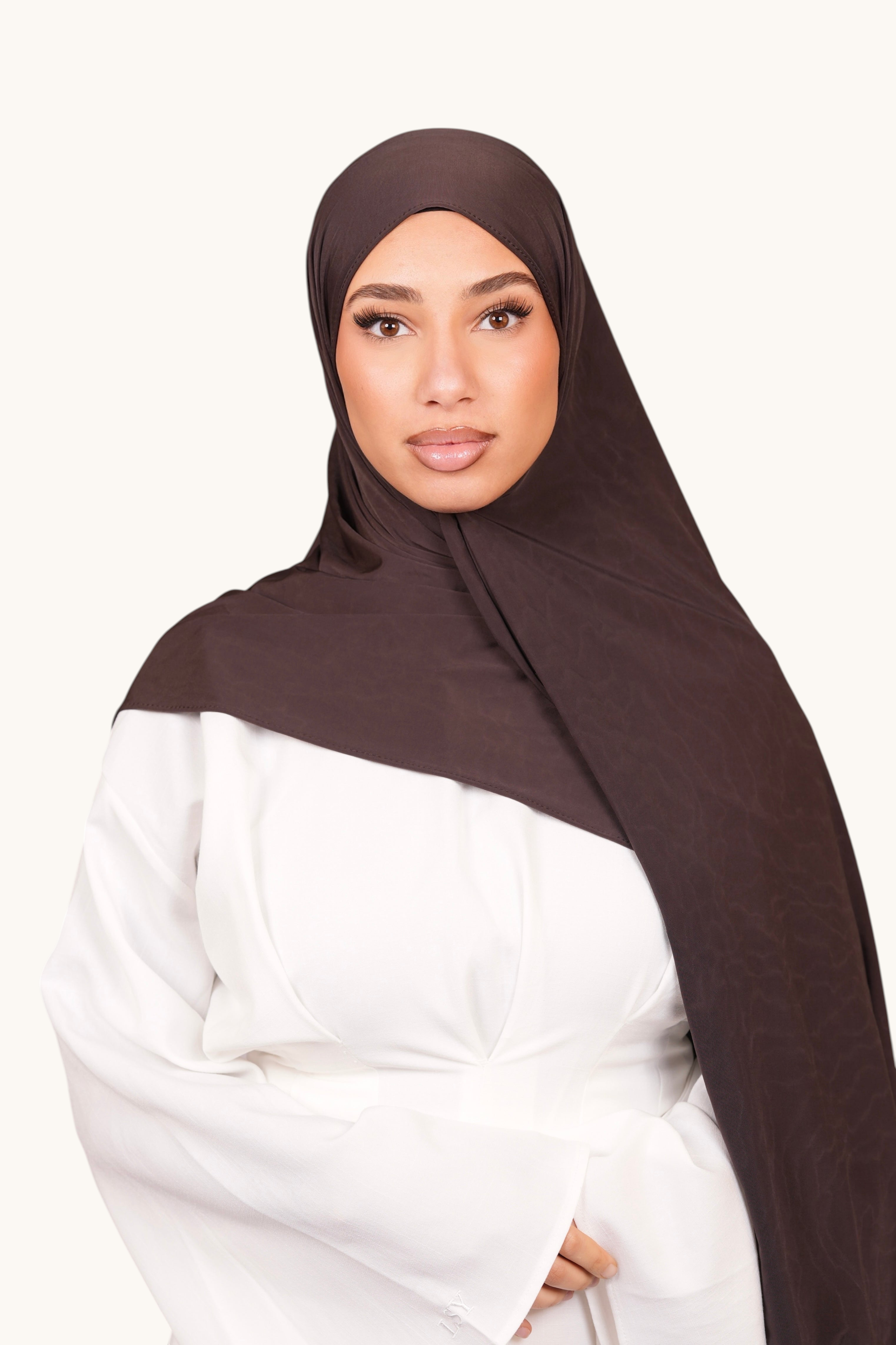 LOSYANA Liquid Jersey hijab in smokey chocolate worn by a woman in a white top, featuring a soft, subtle sheen.