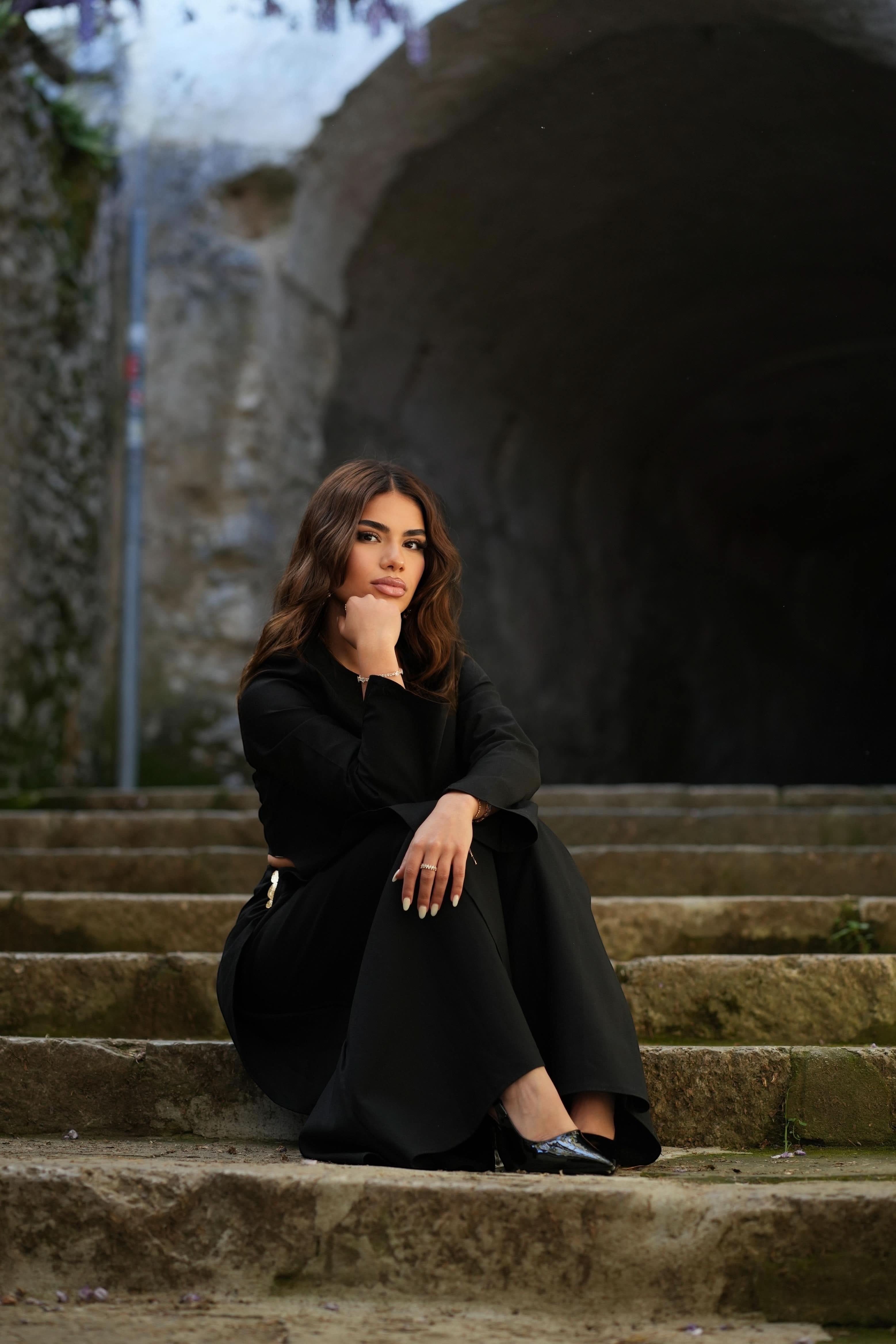 LOSYANA Mediterrance Serenity Set in black linen-cotton blend worn by a woman sitting on stone stairs outdoors