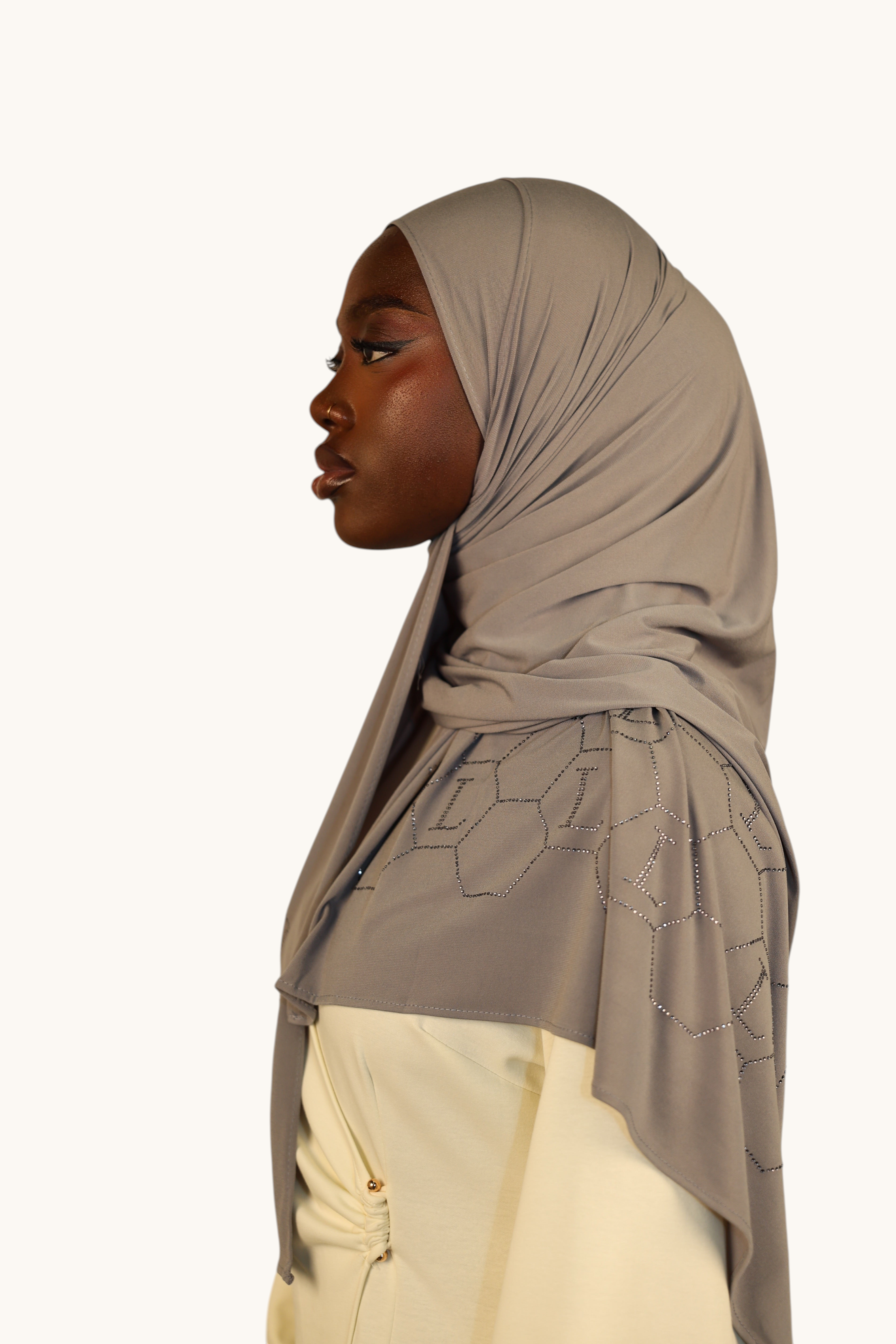 LOSYANA nude grey premium jersey hijab with sparkling rhinestone L-pattern detail worn by a model in profile view