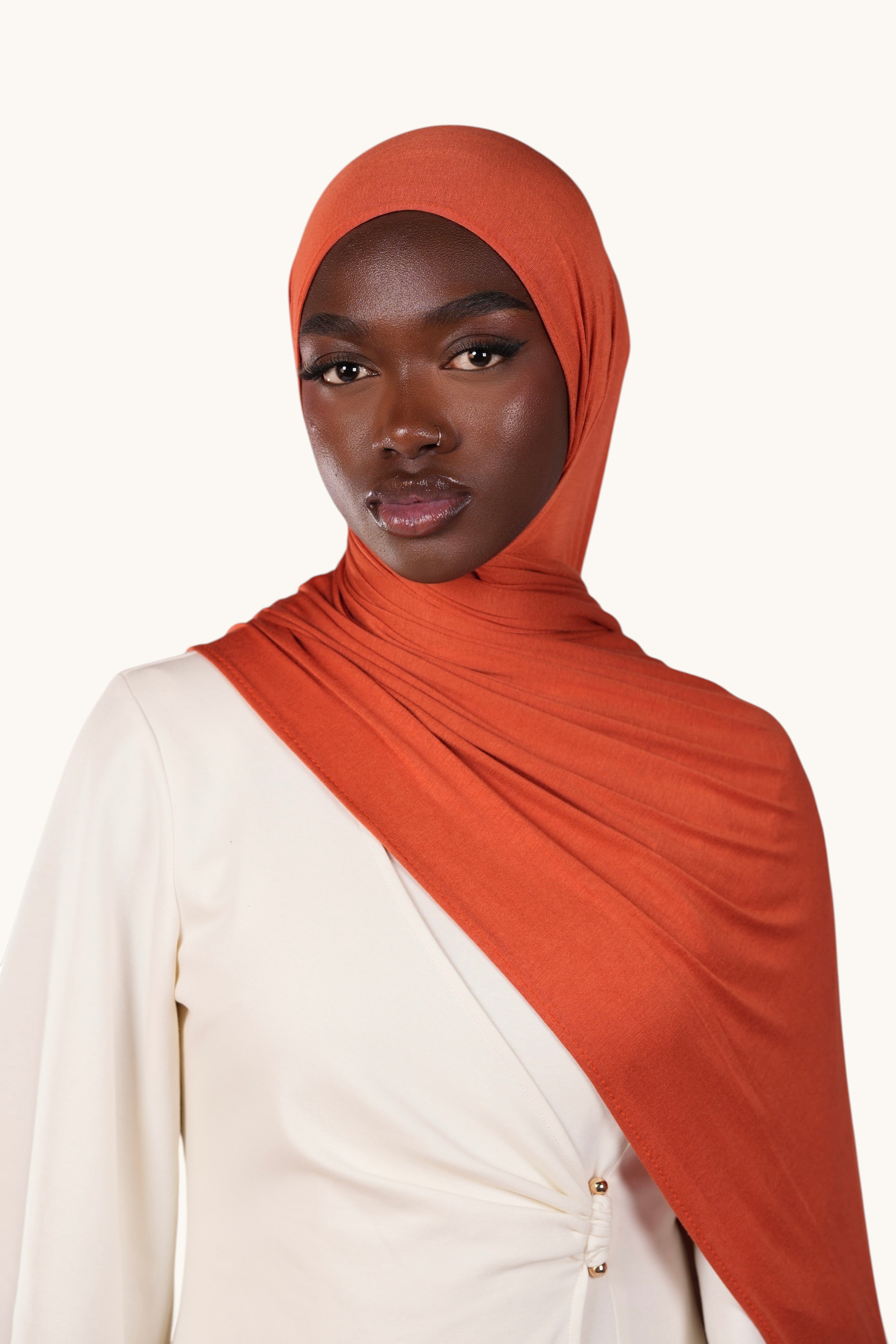 Model wearing a LOSYANA papaya orange bamboo jersey hijab, soft and lightweight fabric with a draped fit.