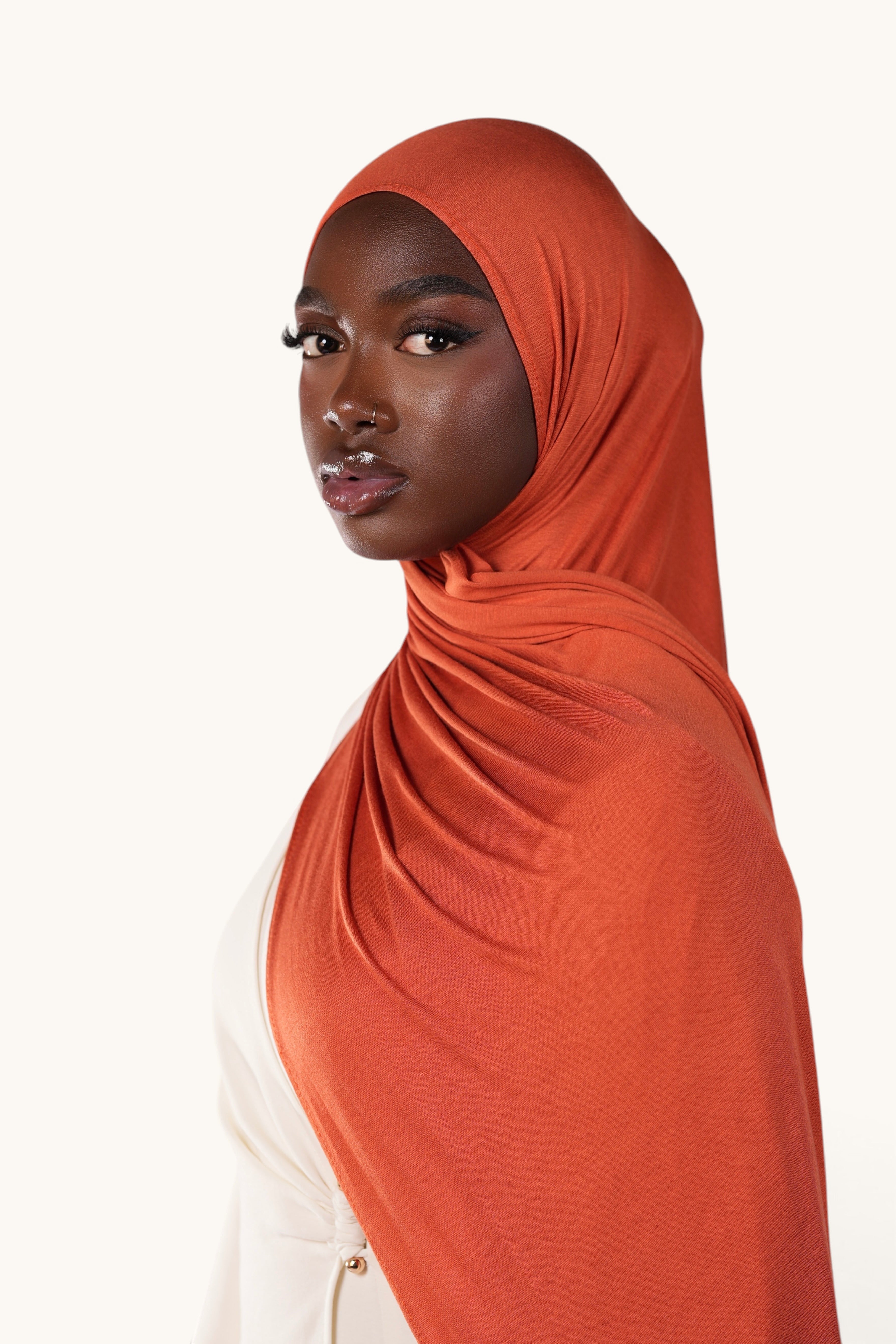 Model wearing a soft papaya orange LOSYANA bamboo jersey hijab, showcasing the lightweight and flowing fabric.