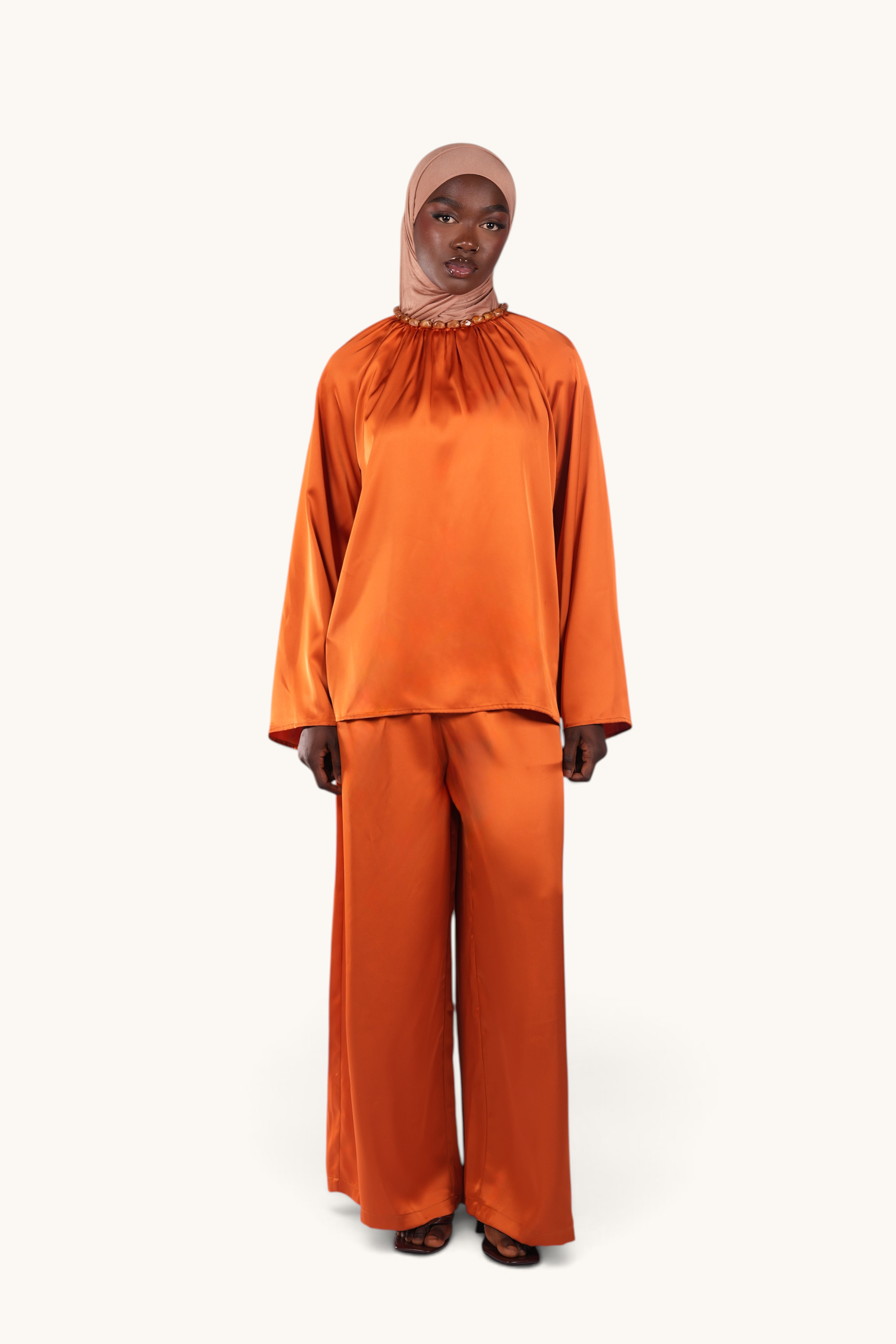 LOSYANA La Marina papaya satin two-piece set featuring a flowing top with an acrylic stone collar and wide-leg pants.