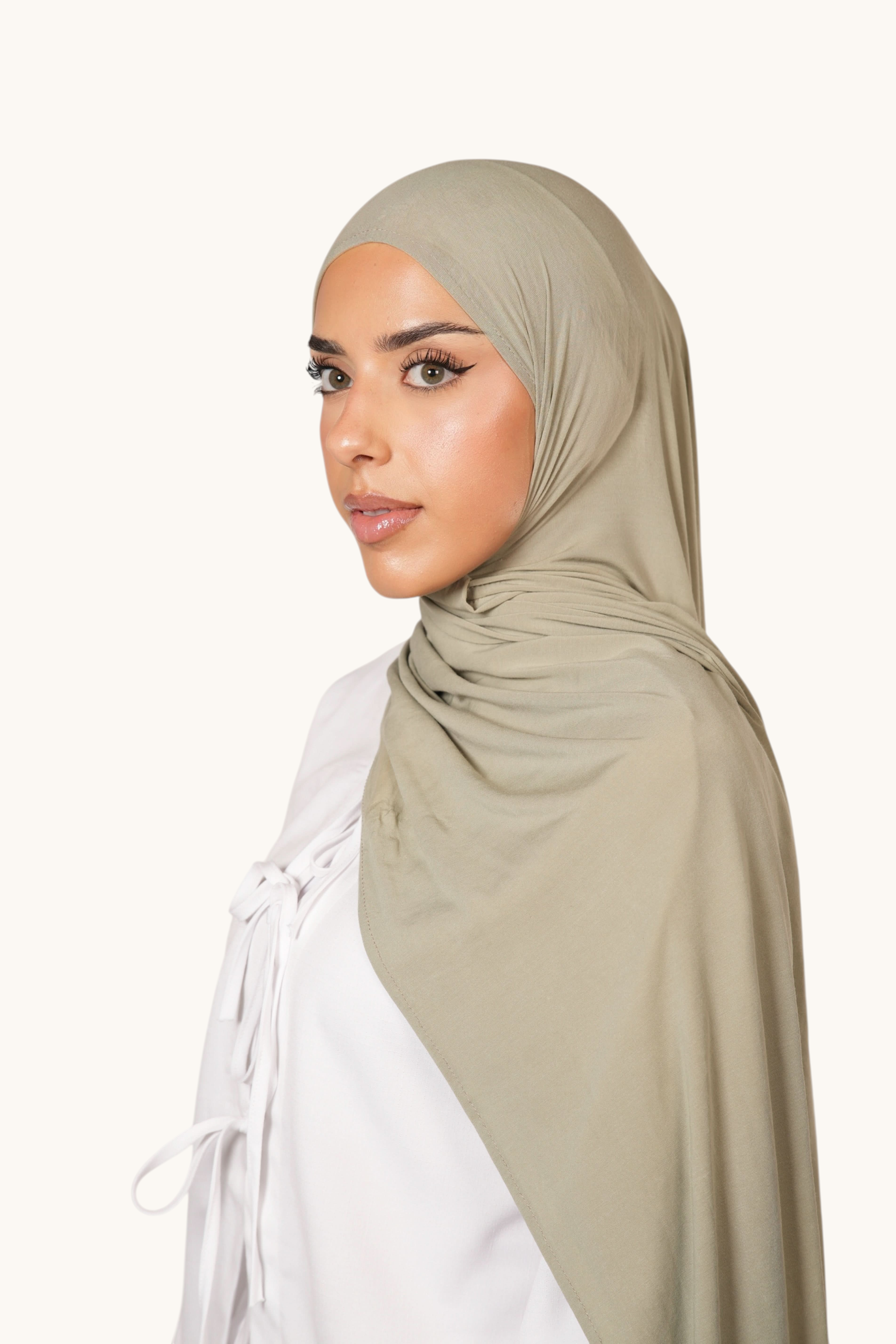 Model wearing a pistachio green LOSYANA Vela Jersey hijab made of soft, breathable fabric in a studio setting.