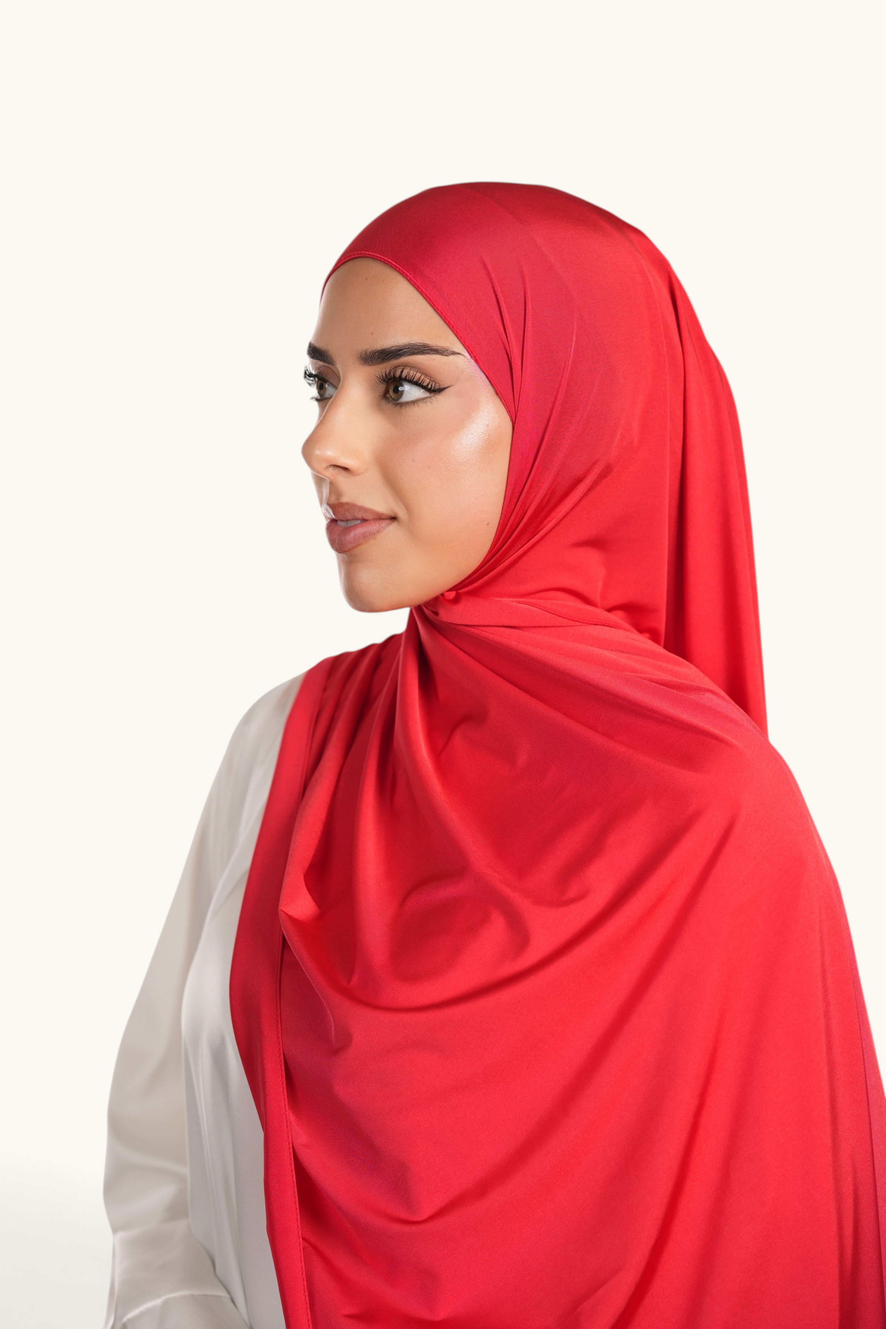 Model wearing a vibrant red LOSYANA satin jersey hijab with a smooth, opaque finish and elegant drape.