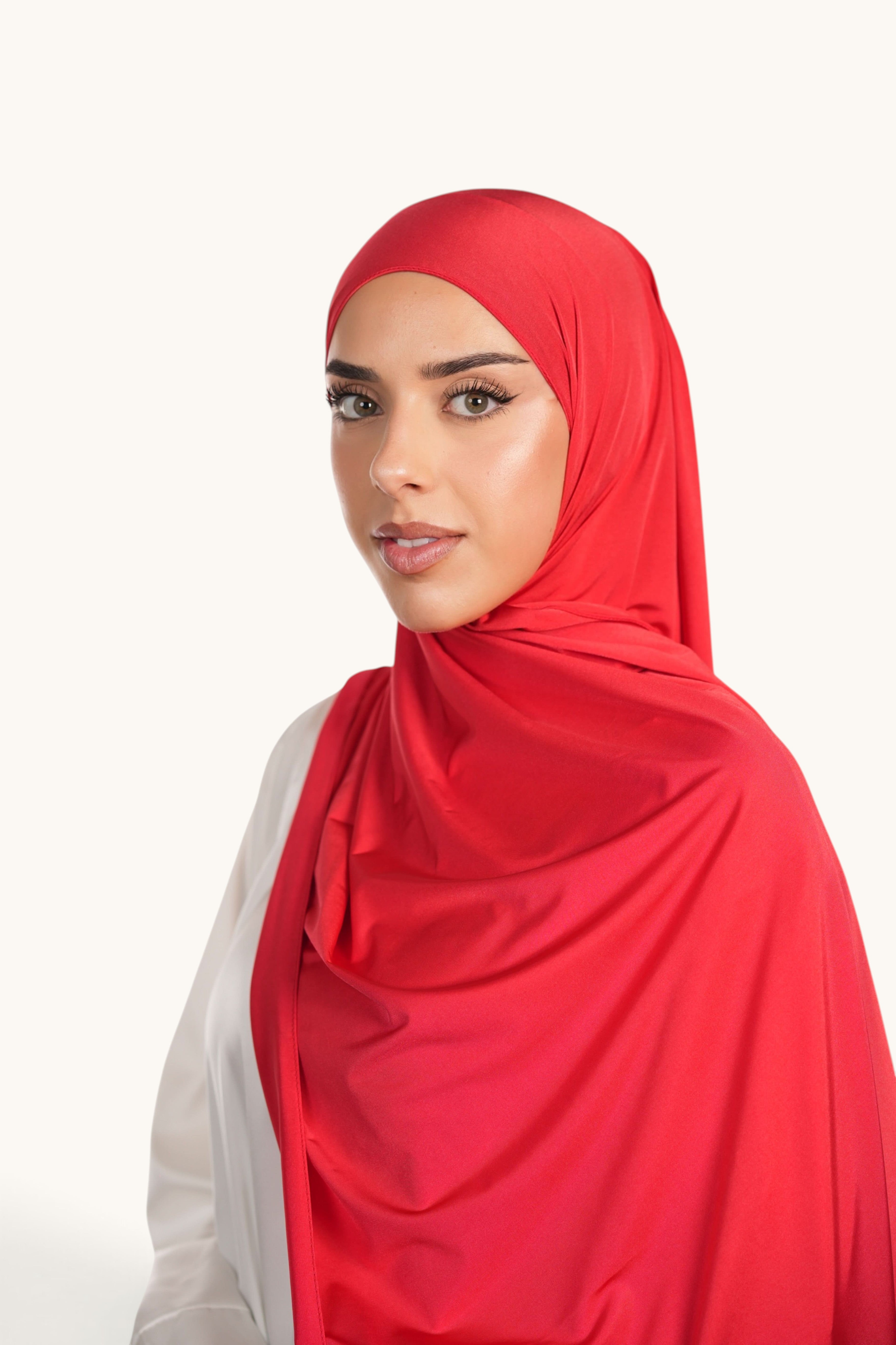 LOSYANA red satin jersey hijab worn by a woman, featuring a smooth, opaque, and non-slip fabric drape.