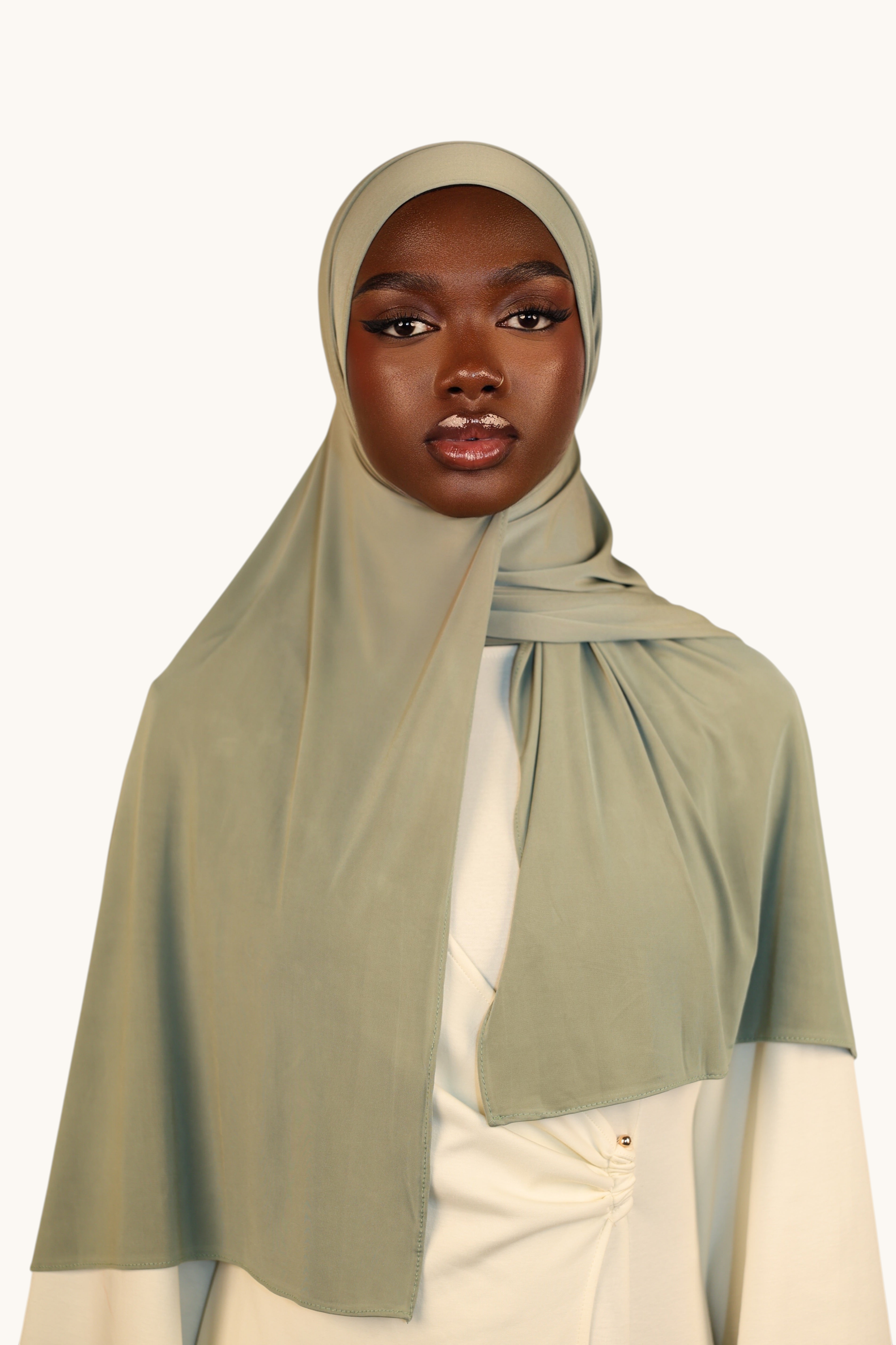 Model wearing a sage green LOSYANA Liquid Jersey hijab with a subtle satin sheen and breathable fabric.