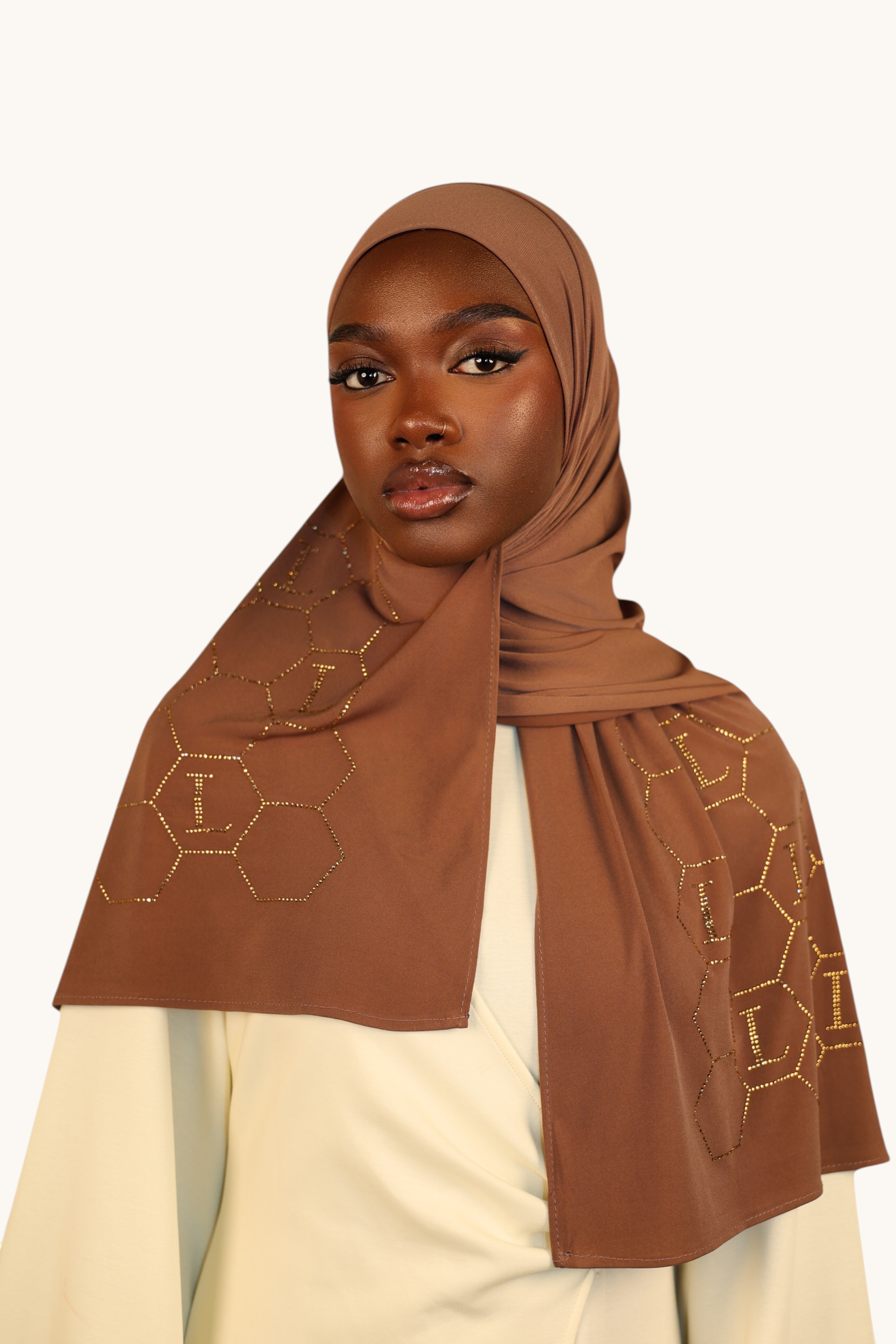 LOSYANA sahara brown premium jersey hijab with gold rhinestone L-logo and honeycomb pattern worn by a model