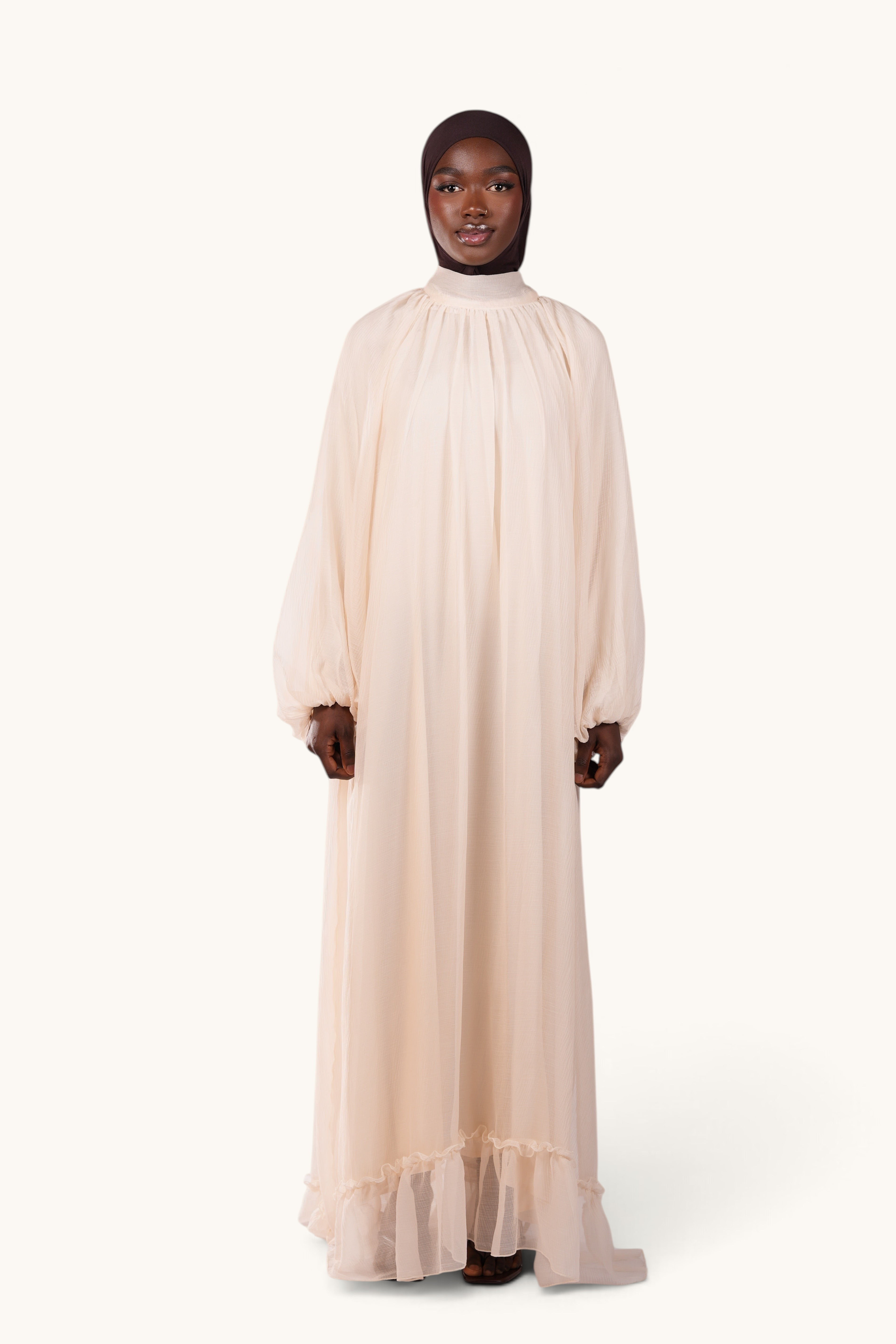 LOSYANA Tenerife ivory crepe maxi dress with high collar, balloon sleeves, and ruffled hem on a model