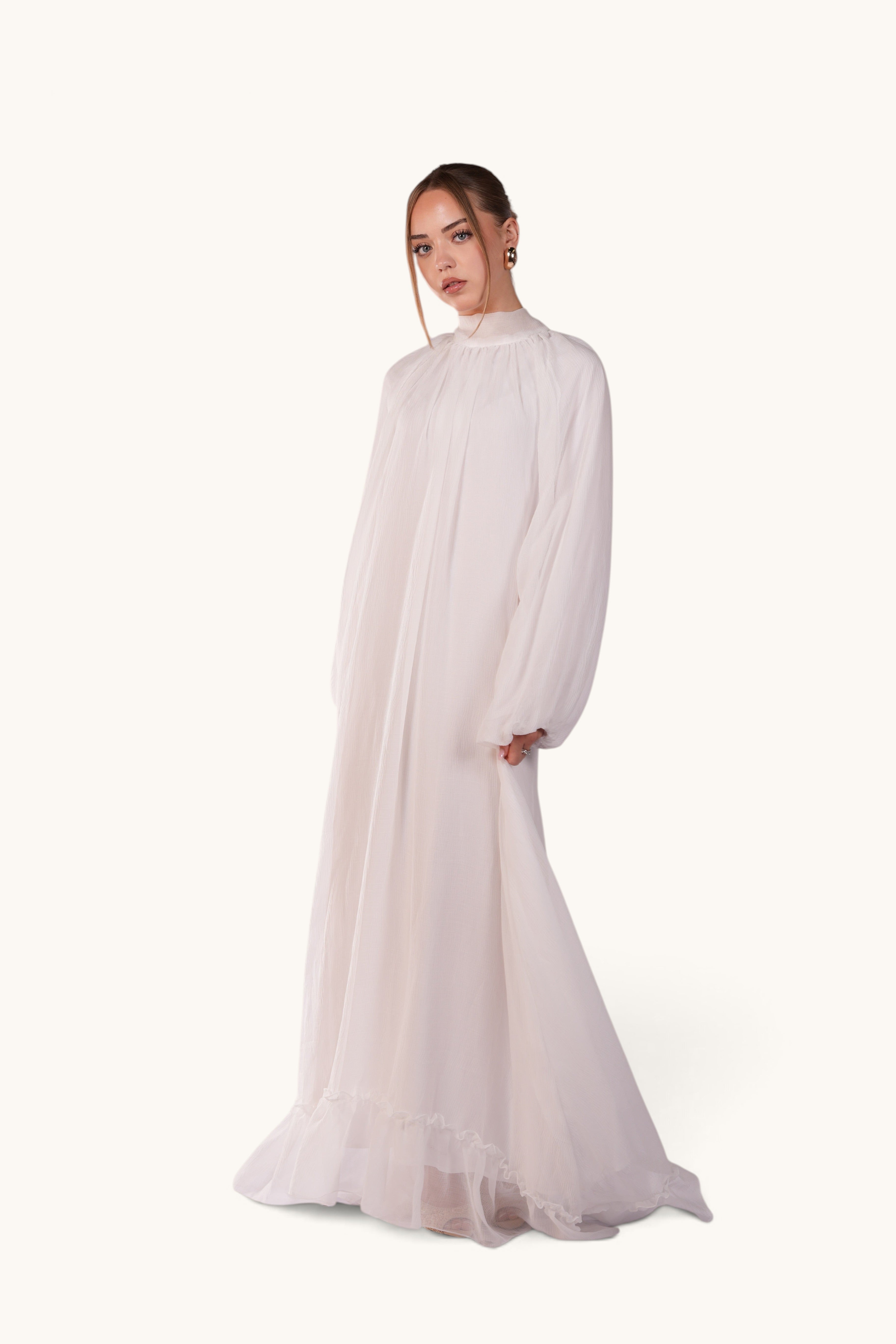 LOSYANA Tenerife white crepe maxi dress with high collar, balloon sleeves, and ruffled hem worn by a model