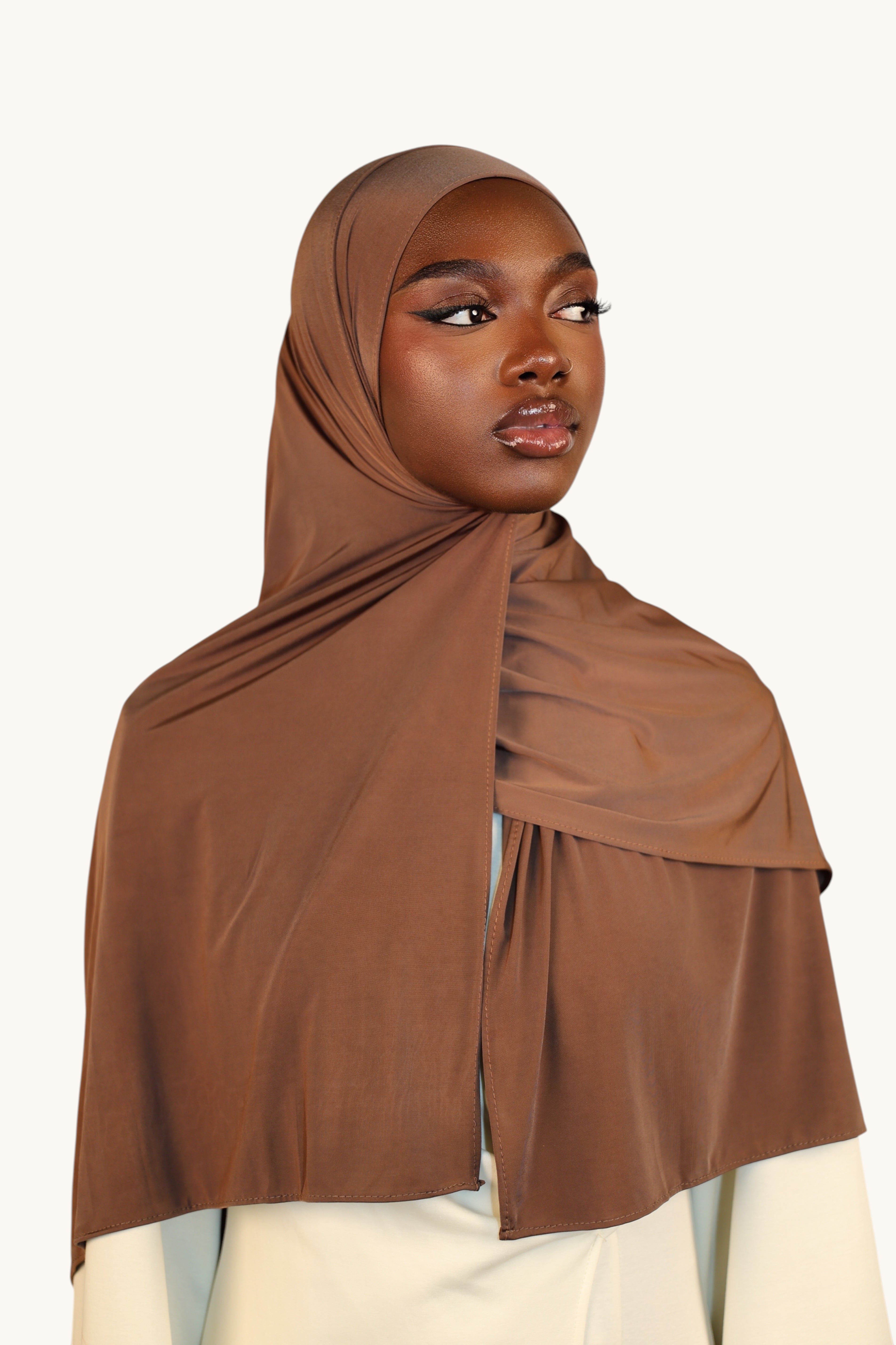 LOSYANA toffee liquid jersey hijab worn by a model, featuring a lightweight, slightly glossy breathable fabric.