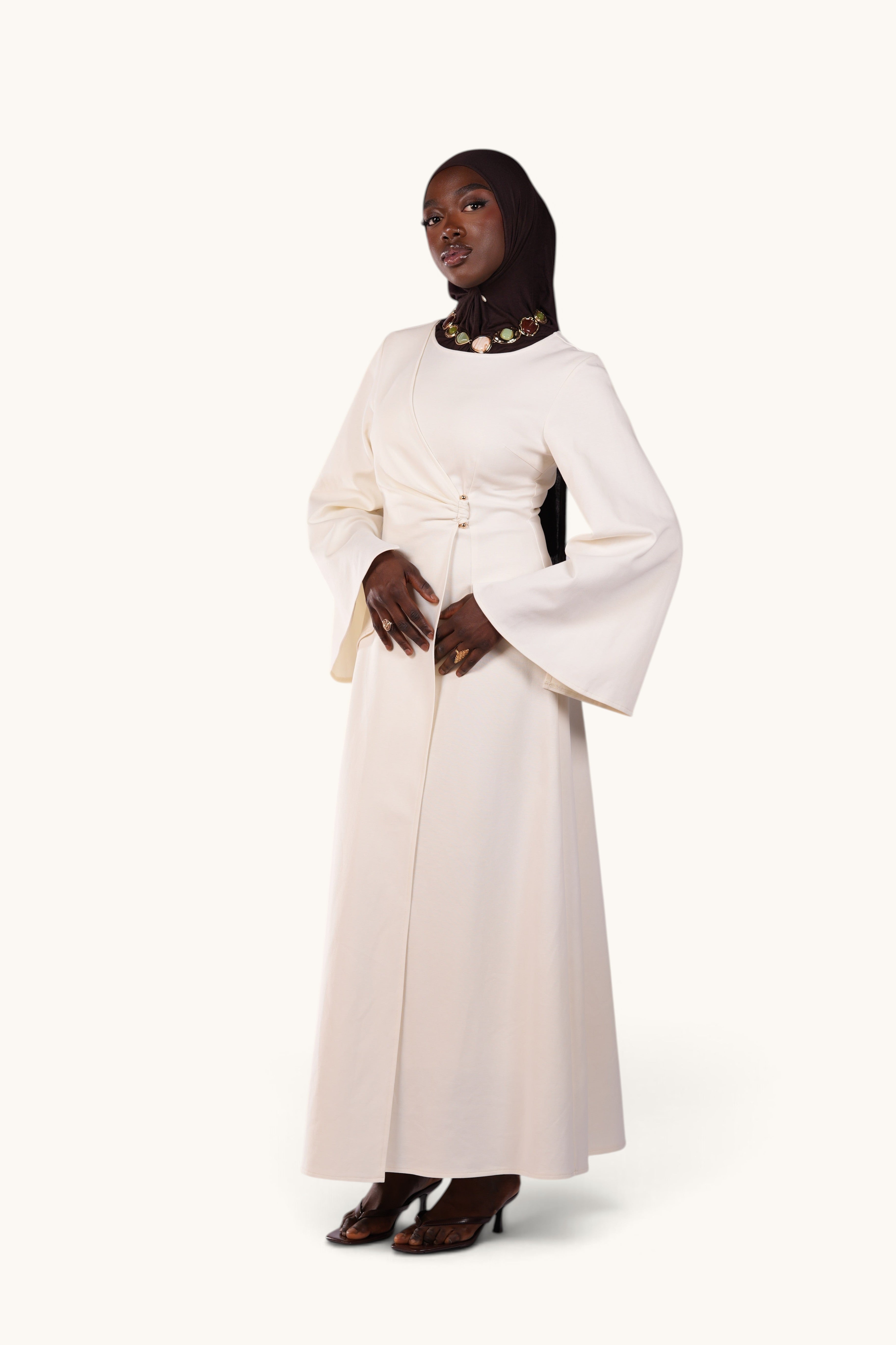LOSYANA Valencia cream maxi dress with trumpet sleeves and gold waist detail worn by a model in a hijab