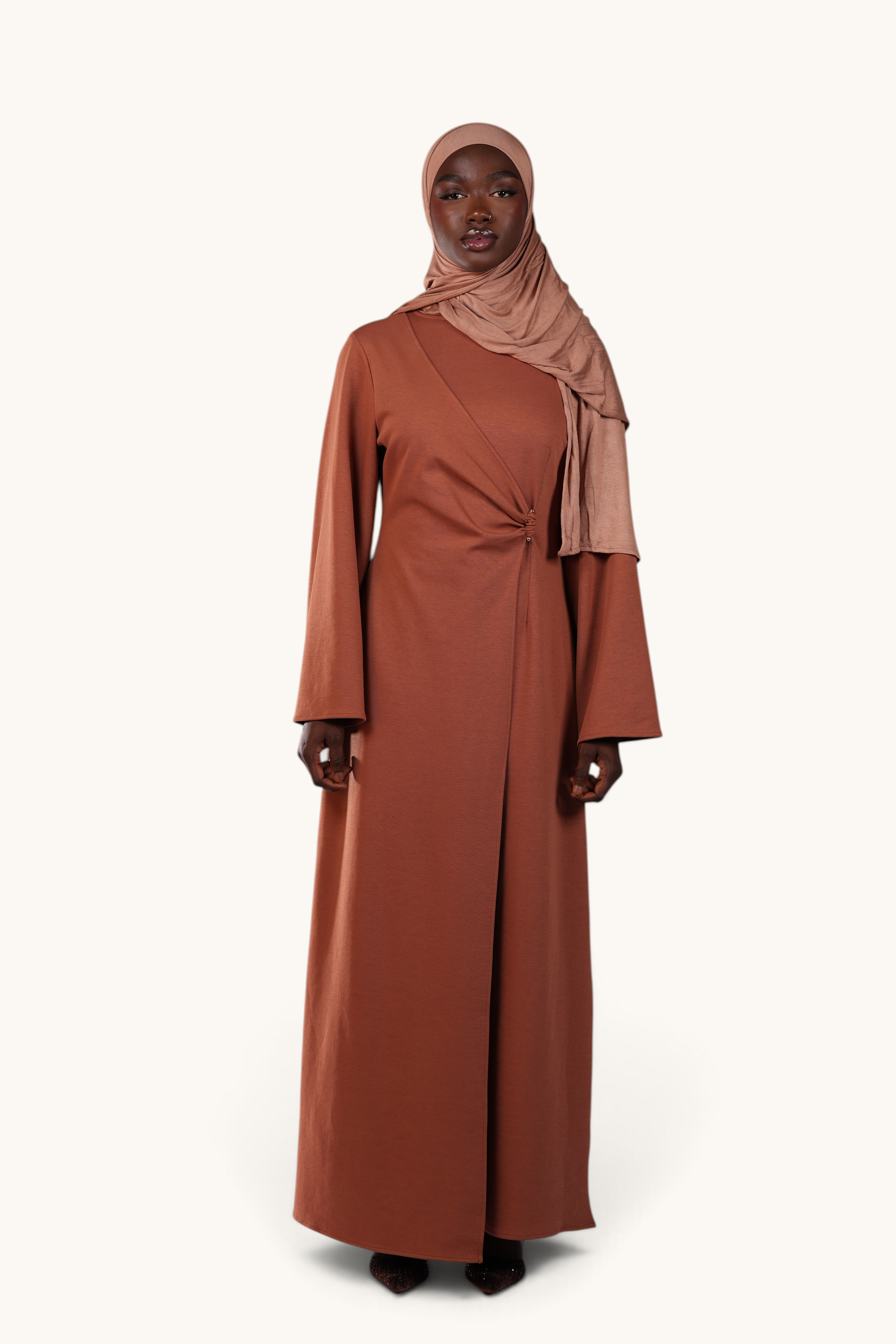 LOSYANA Valencia terracotta maxi dress with trumpet sleeves and gold waist detail worn by a model in a hijab