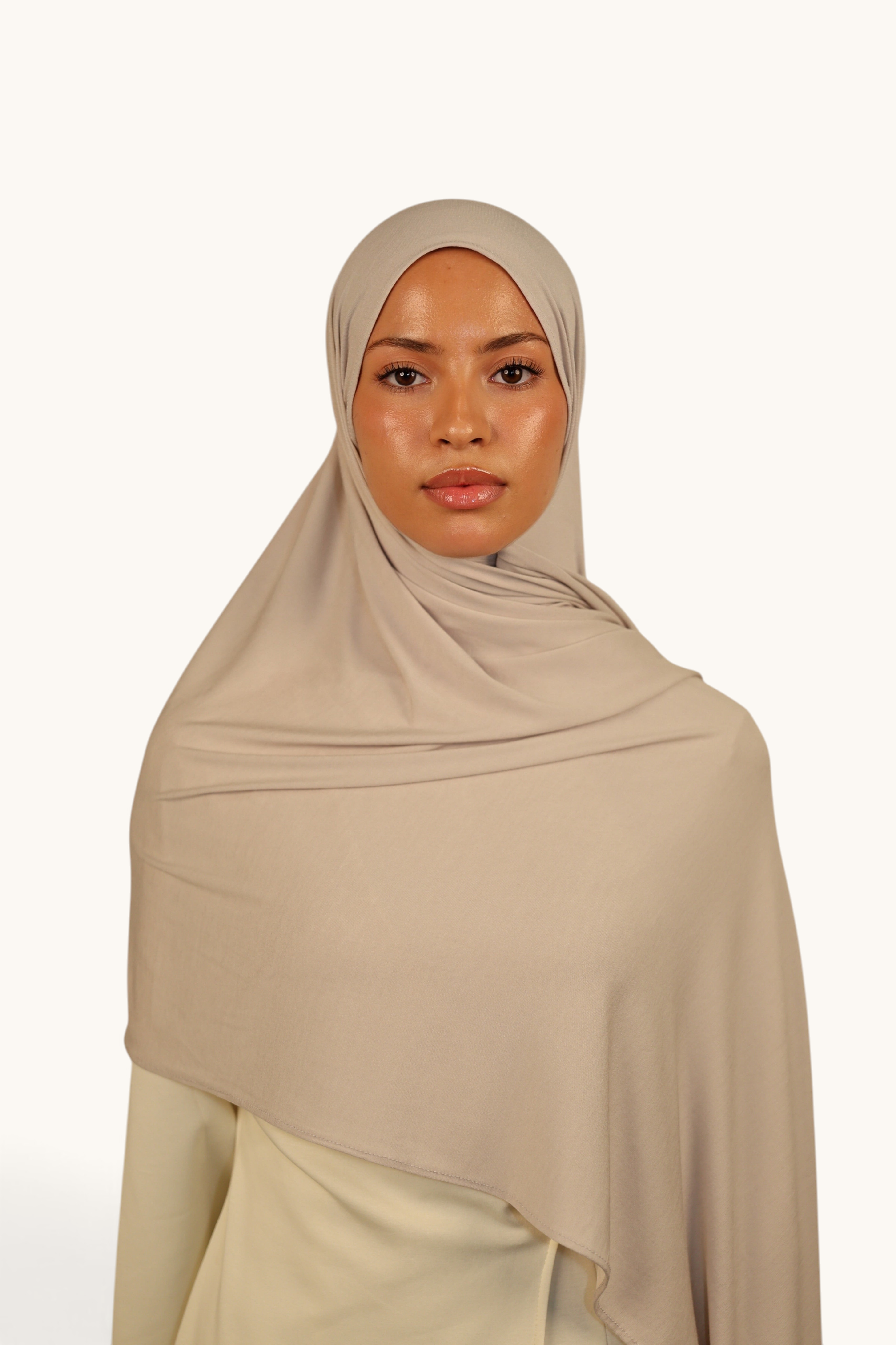 Model wearing a LOSYANA Vela Jersey hijab in ash beige, made from soft, lightweight, breathable fabric.