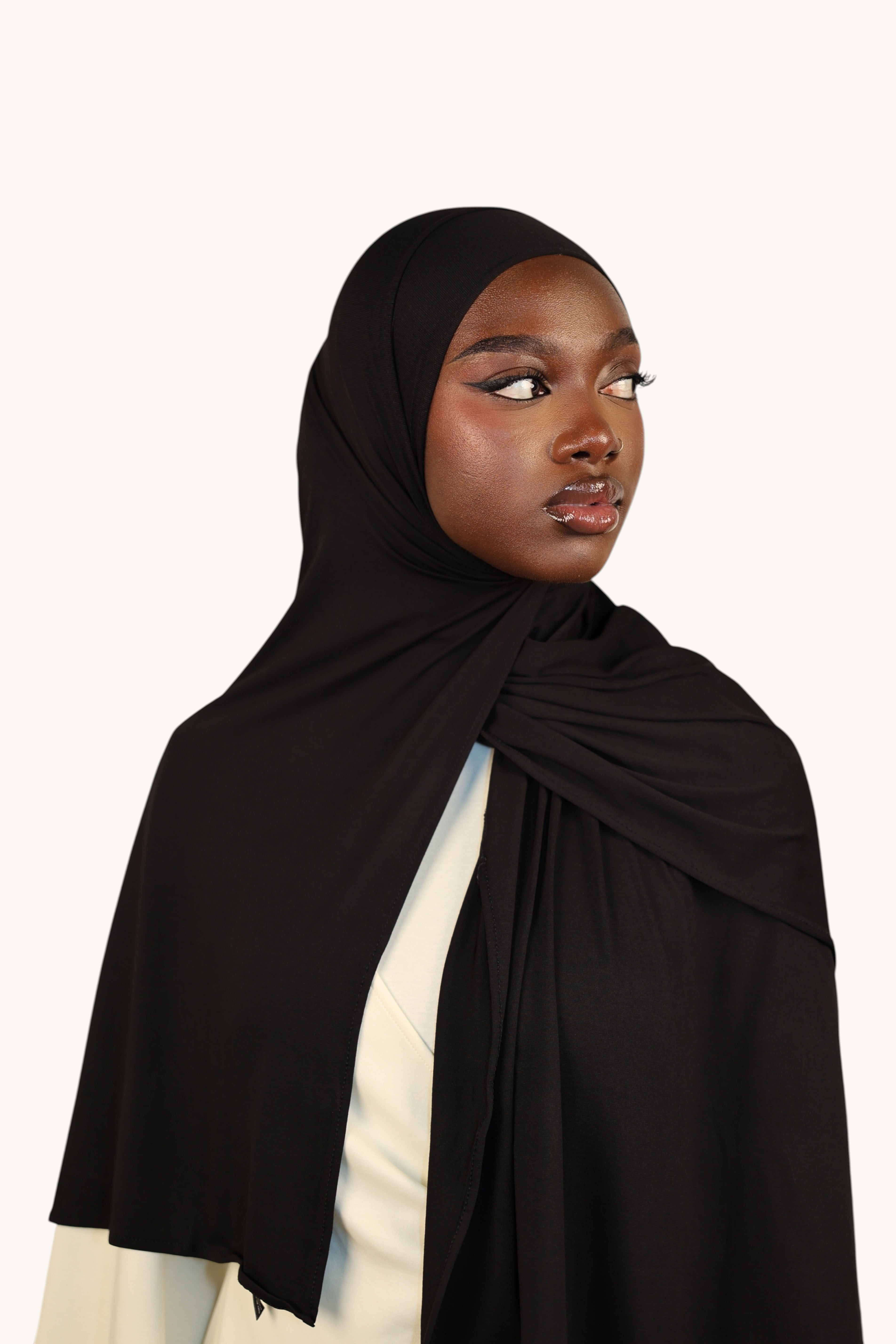 Model wearing a black LOSYANA Vela Jersey hijab made of soft, breathable fabric, styled elegantly over shoulders.