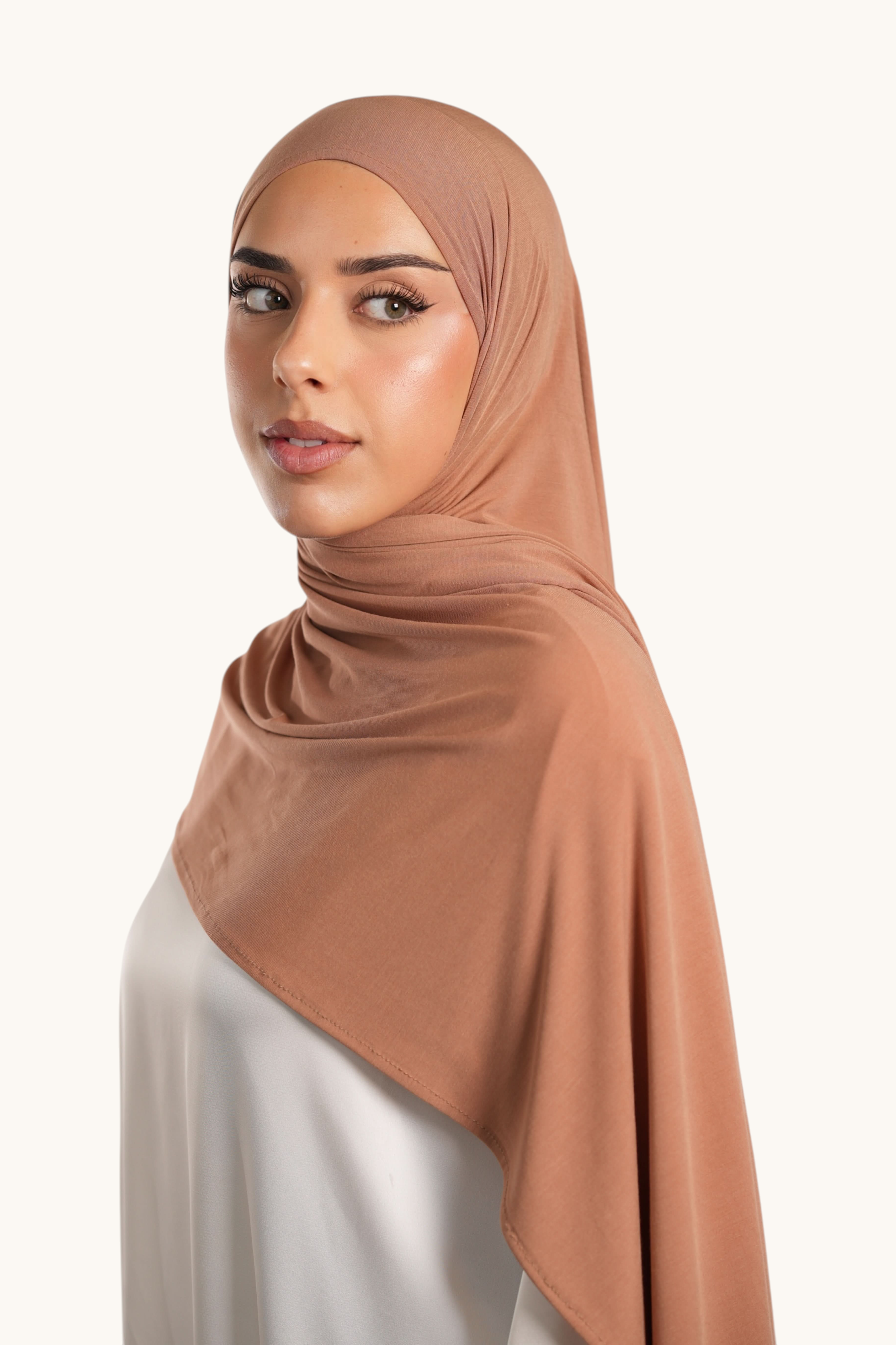 Model wearing a caramel LOSYANA Vela Jersey hijab, a lightweight and breathable fabric wrap for elegant styling.