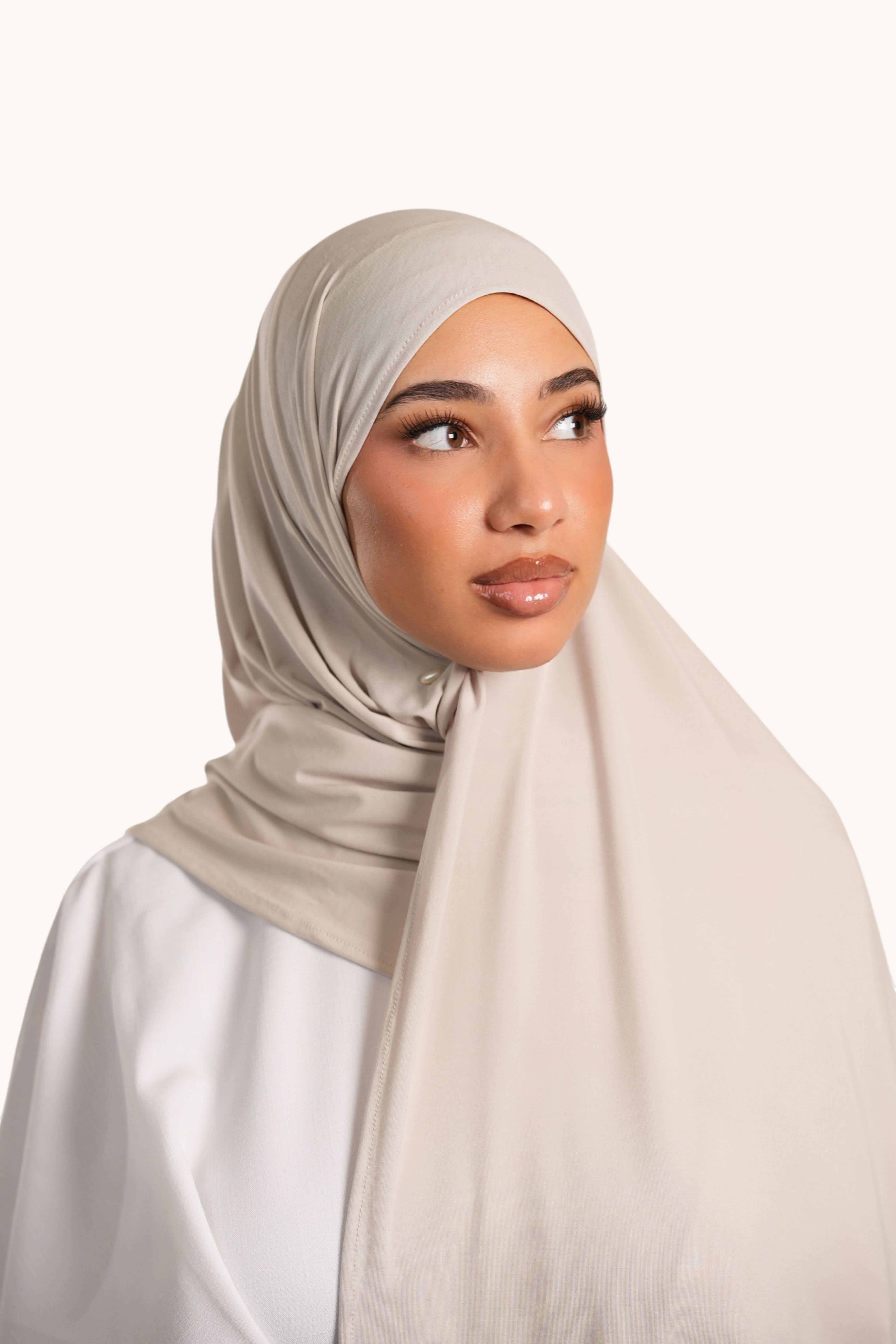 Model wearing a light beige LOSYANA Vela Jersey hijab made of soft, breathable fabric, styled elegantly.