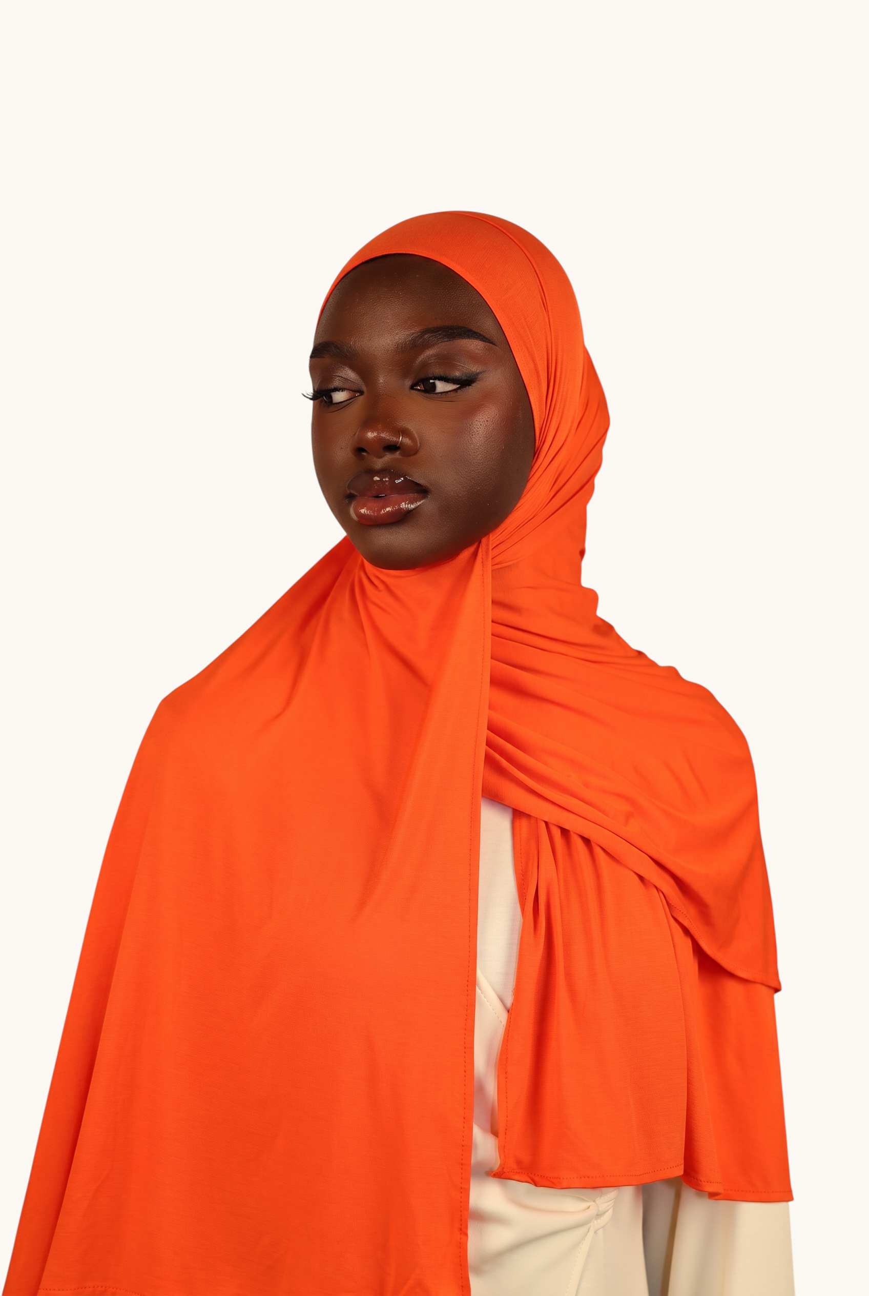 Model wearing a vibrant orange LOSYANA Vela Jersey hijab made of soft, breathable fabric, styled elegantly.