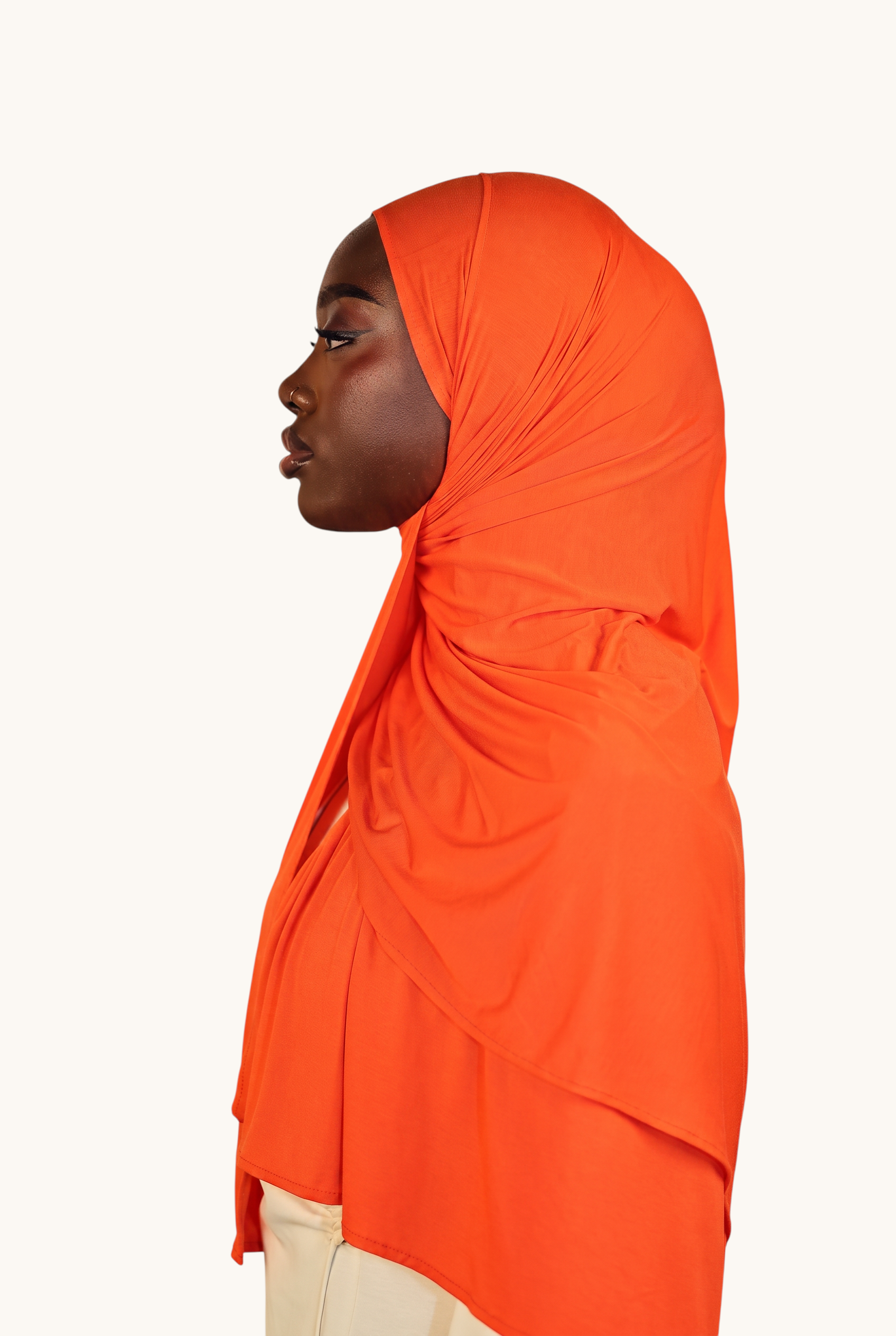 Model wearing a vibrant orange LOSYANA Vela Jersey hijab, showcasing the soft, lightweight fabric in a side profile.