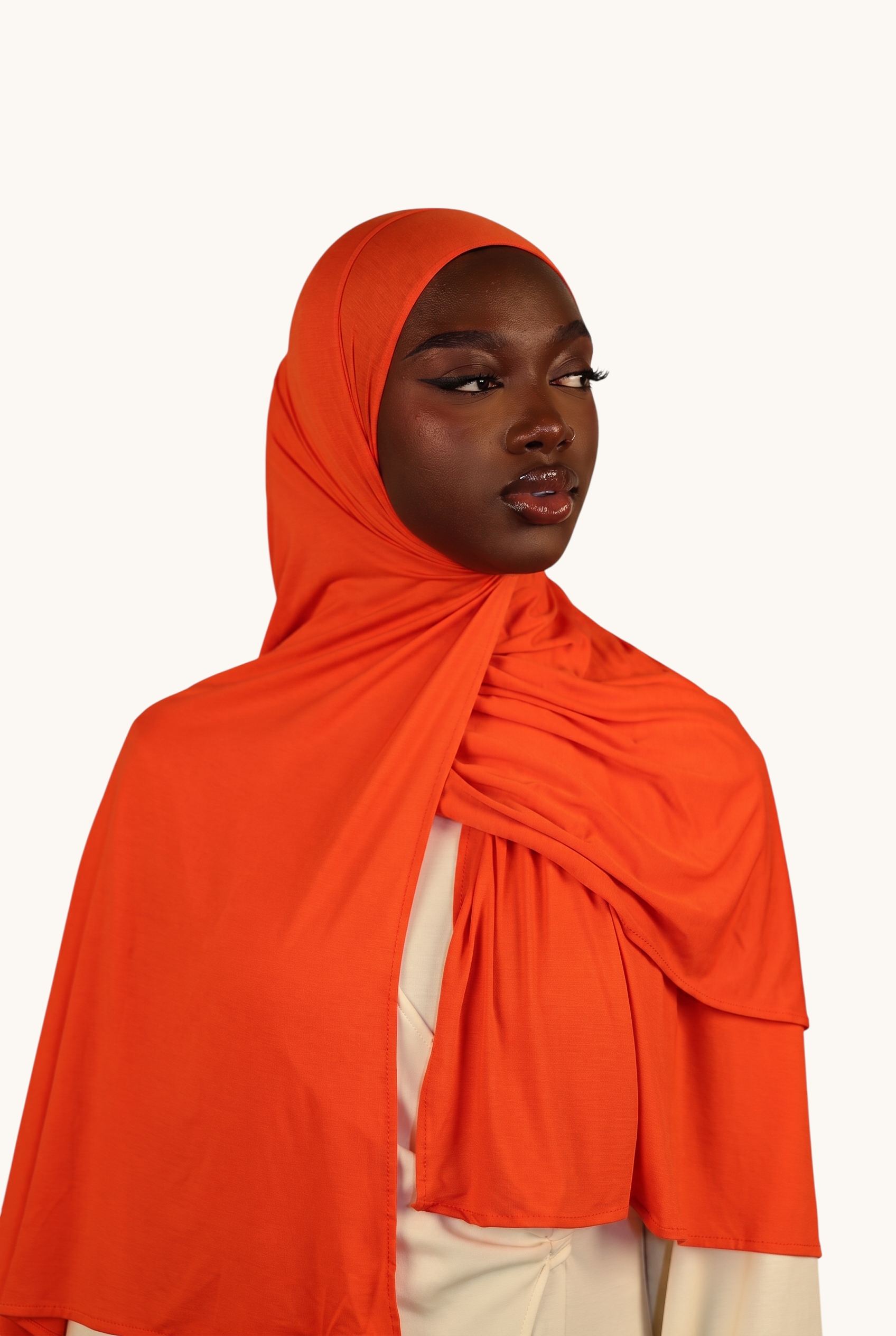 Model wearing a vibrant orange LOSYANA Vela Jersey hijab made of soft, breathable fabric, styled elegantly.