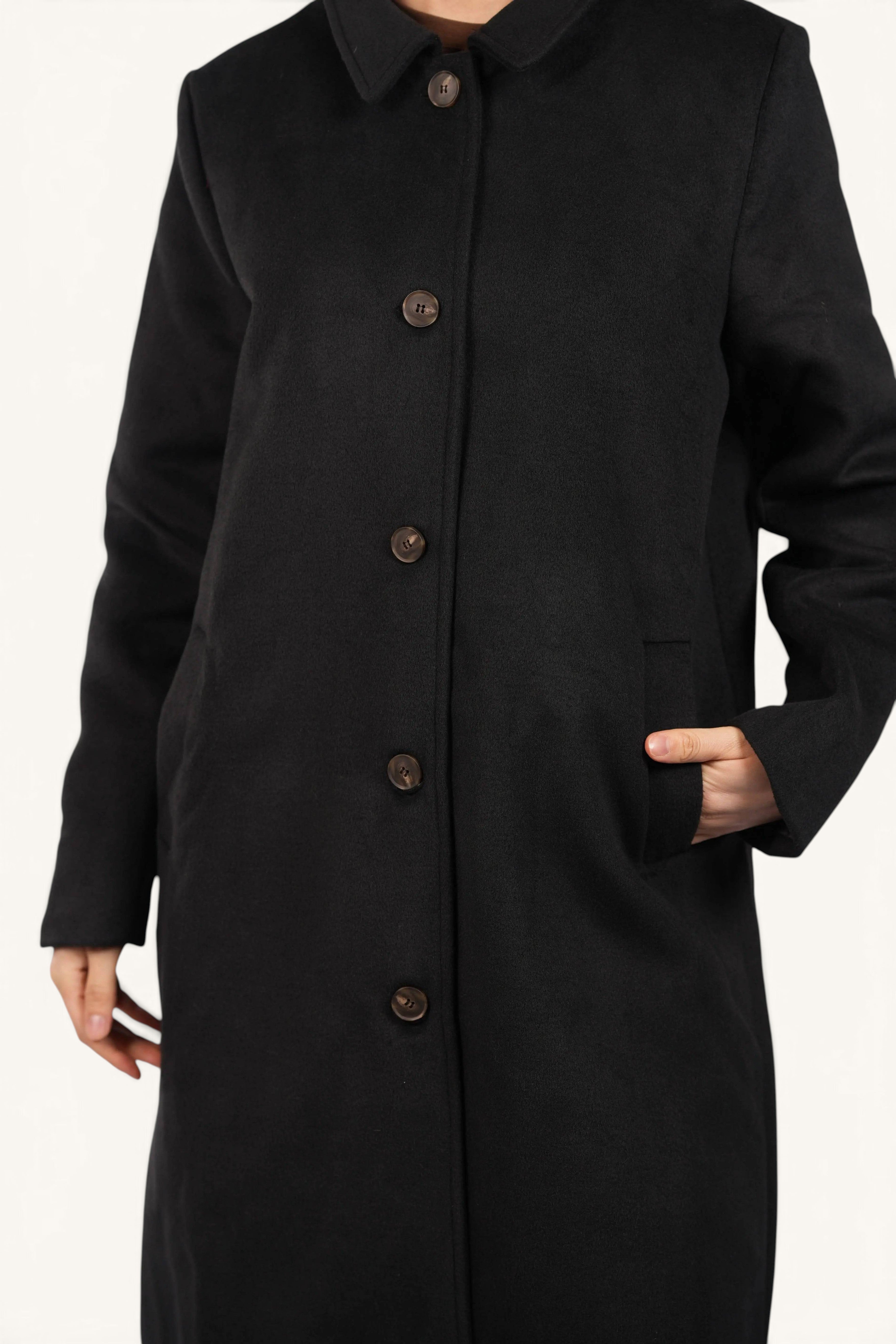 LOSYANA The Vienna Coat in black featuring a classic collar, button-up front, and side pockets on a model