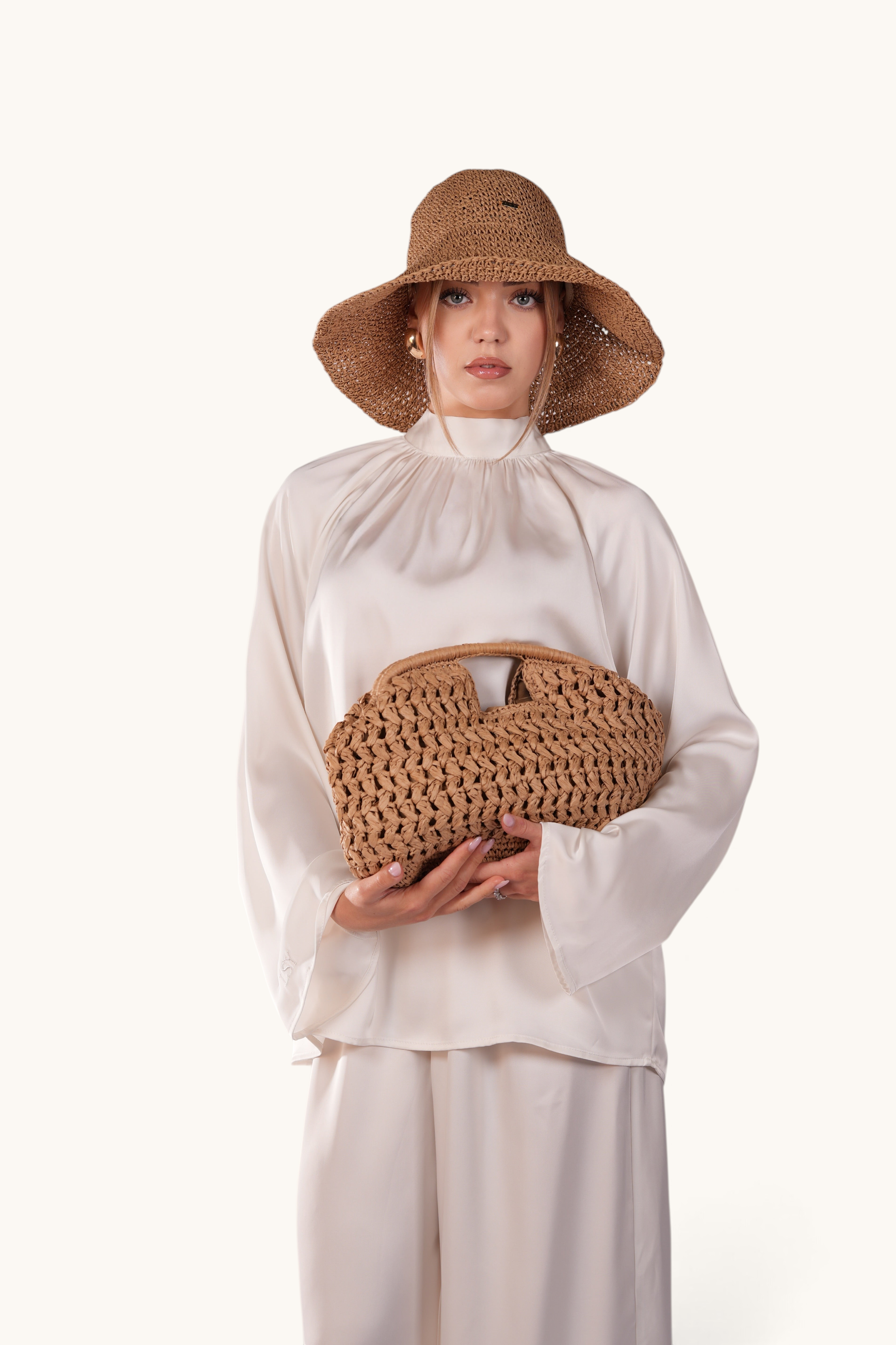 Model wearing a LOSYANA walnut straw hat with adjustable brim, paired with a matching woven handbag and silk blouse.