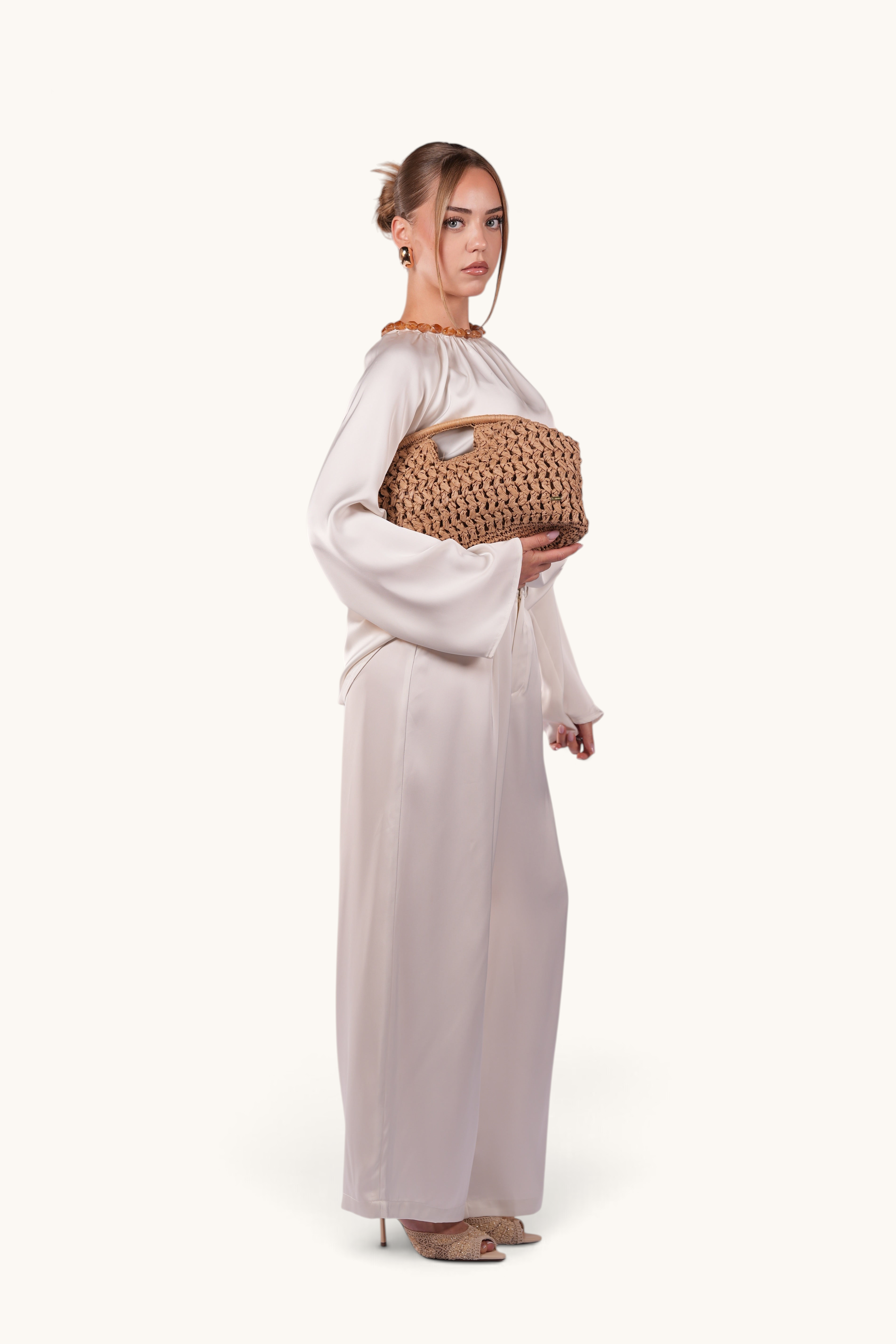 Model wearing LOSYANA white satin set holding a walnut-coloured handcrafted woven straw bag