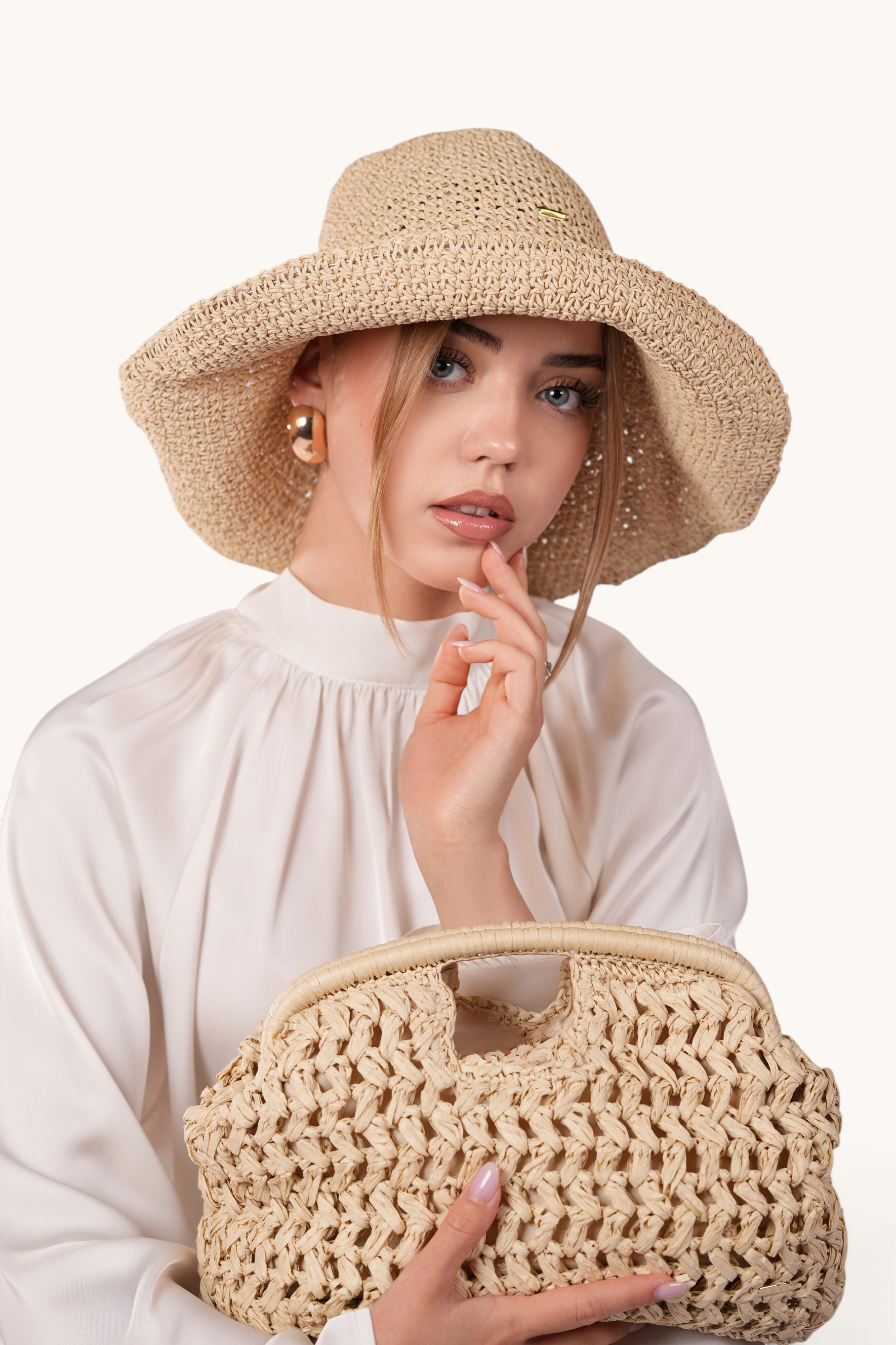 LOSYANA model wearing a beige woven straw hat and holding a matching handcrafted beige straw handbag